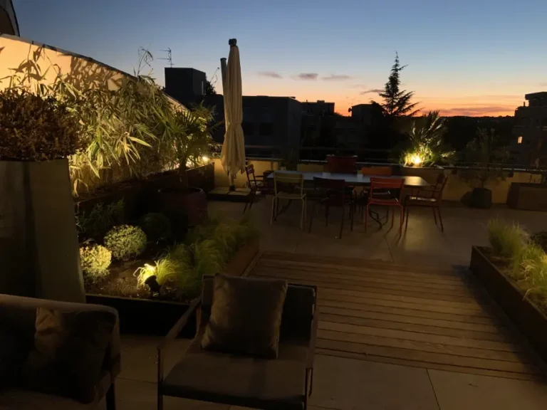 vue d'une terrasse en ville avec coucher de soleil et des lumières qui éclairent le décor