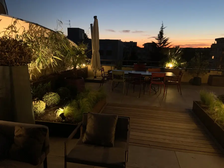 vue d'une terrasse en ville avec coucher de soleil et des lumières qui éclairent le décor