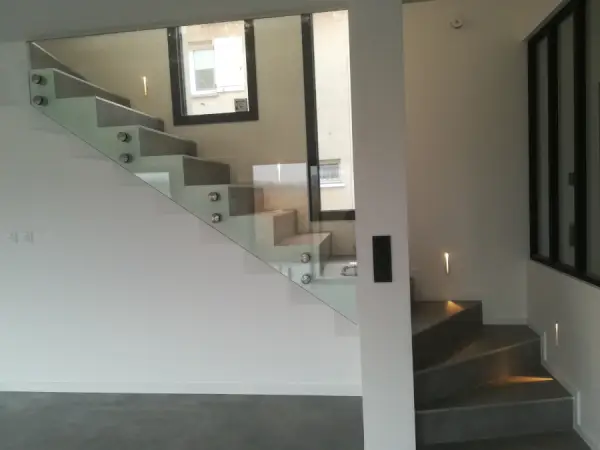un escalier avec une vitre en verre et un bel éclairage avec des leds qui éclairent les marchent