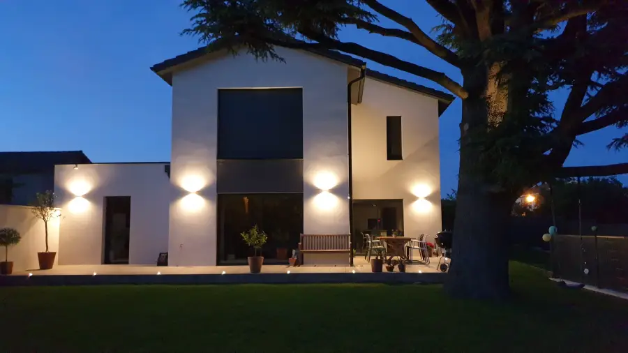 une façade de maison et une terrasse qui sont joliment éclairées par des luminaires