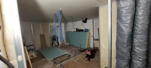 une pièce de maison en rénovation, l'électricité et plomberie préparées pour la pose du placo-plâtre. des gaines de vmc (ventilation) sont aussi installées