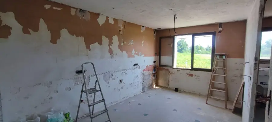une pièce de maison en travaux, l'électricien est en train de rénover l'installation électrique en scellant les gaines électriques et les boites d'encastrement